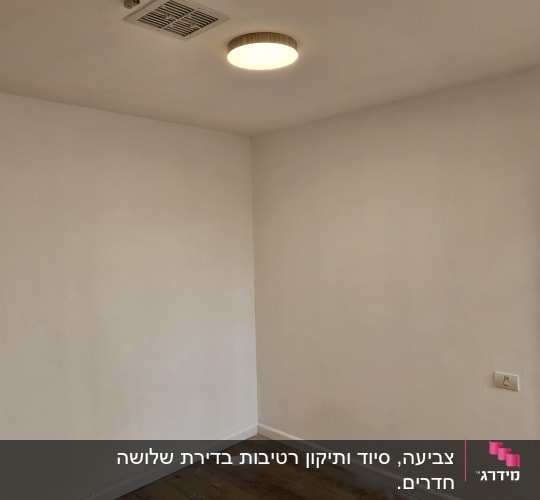 חדר צבוע עם קירות לבנים וכלי צבע על הרצפה